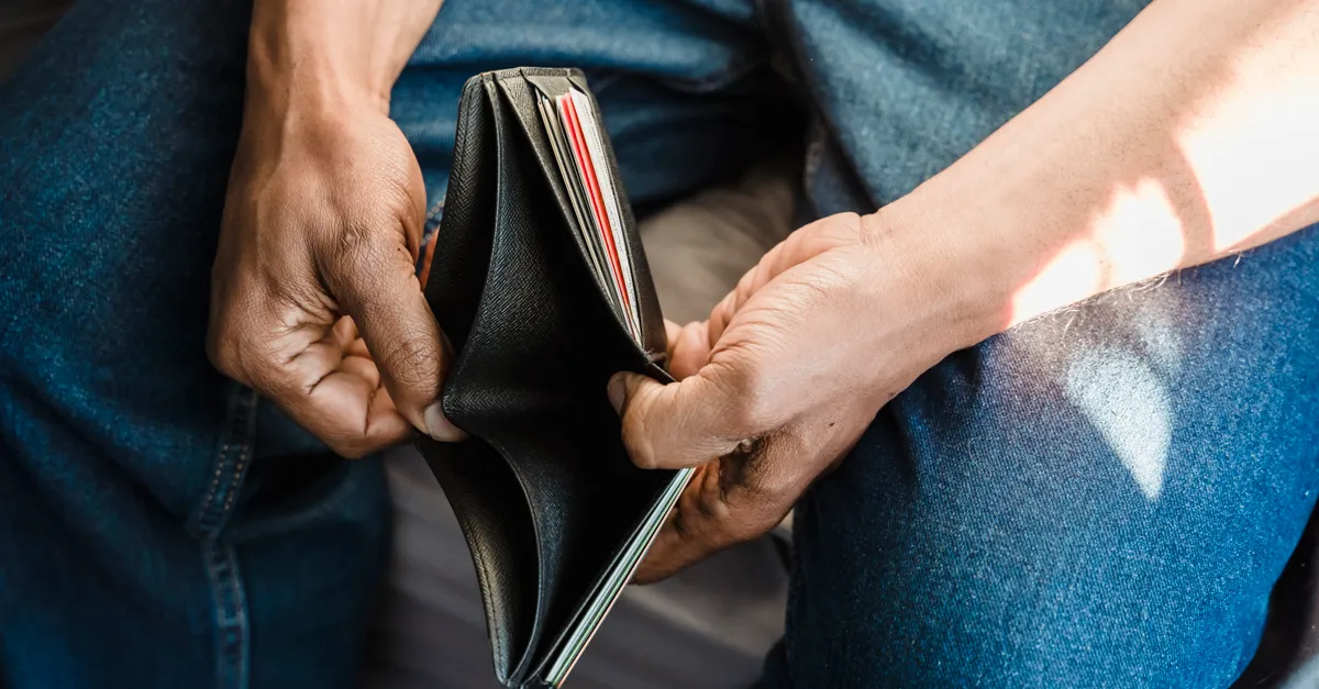 Close-up of a man holding an empty wallet, symbolizing financial crisis and hardship.