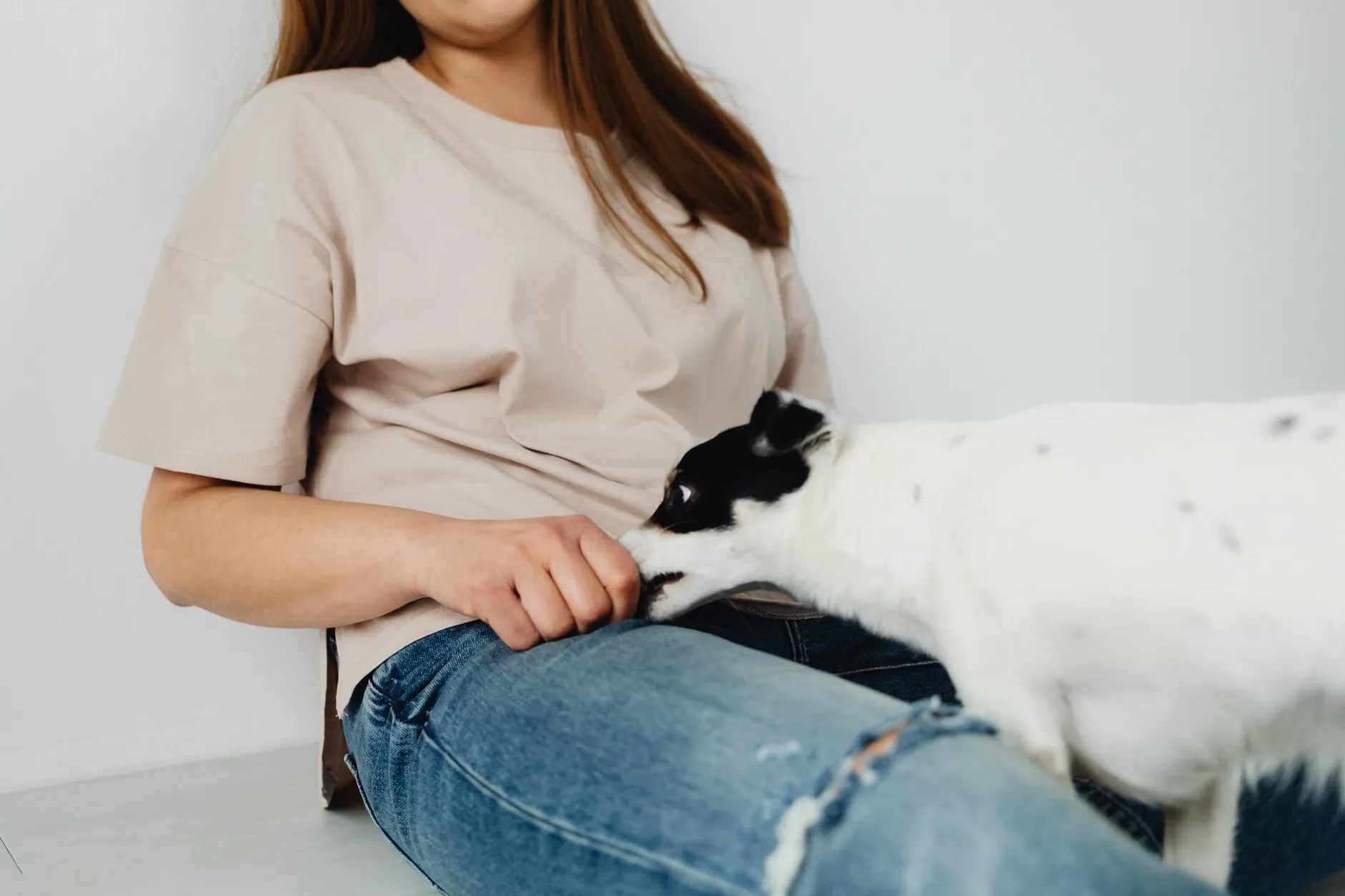A woman sitting with her pet dog indoors on a white background, showcasing relaxation and companionship.