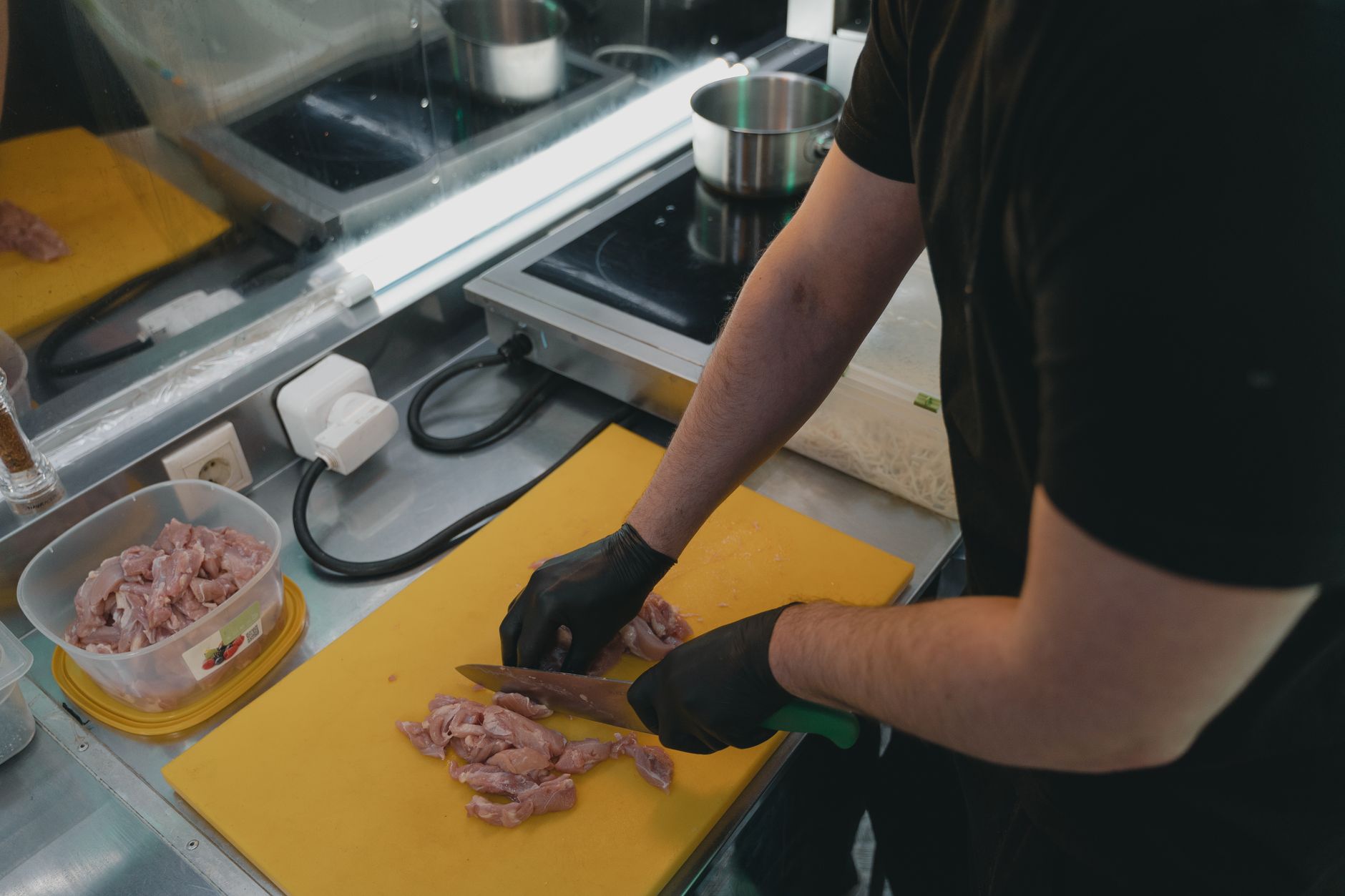 Man slicing raw meat on a yellow cutting board in a modern kitchen setting.